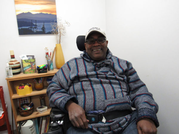 Smiling man in wheelchair in front of art supplies