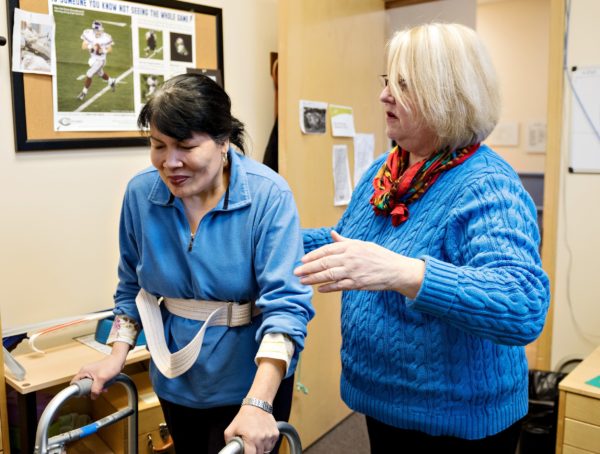 Occupational therapist helps a participant walk.